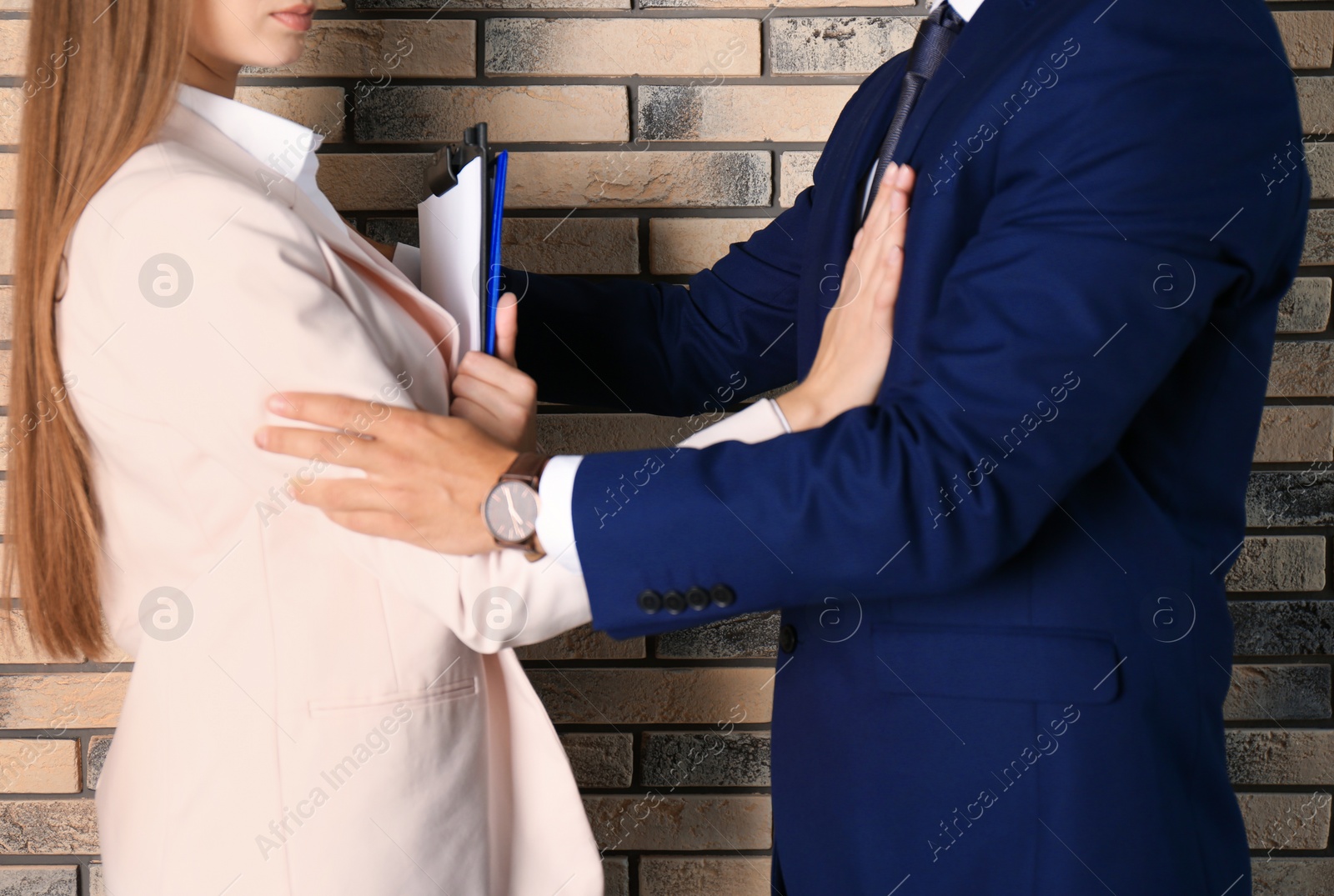 Photo of Boss molesting his female secretary near brick wall, closeup. Sexual harassment at work