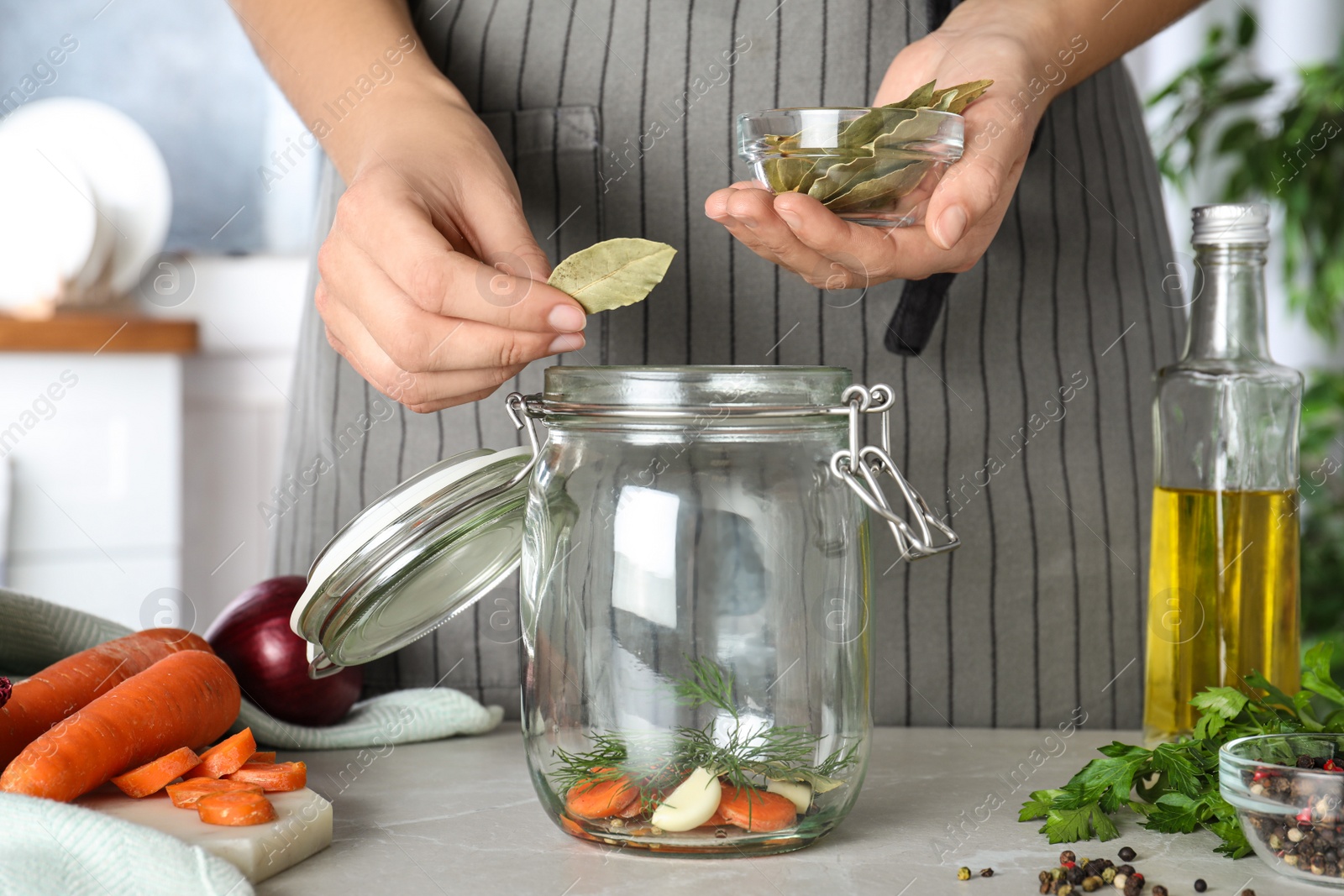 Photo of Woman putting bay leaves at marble table, closeup