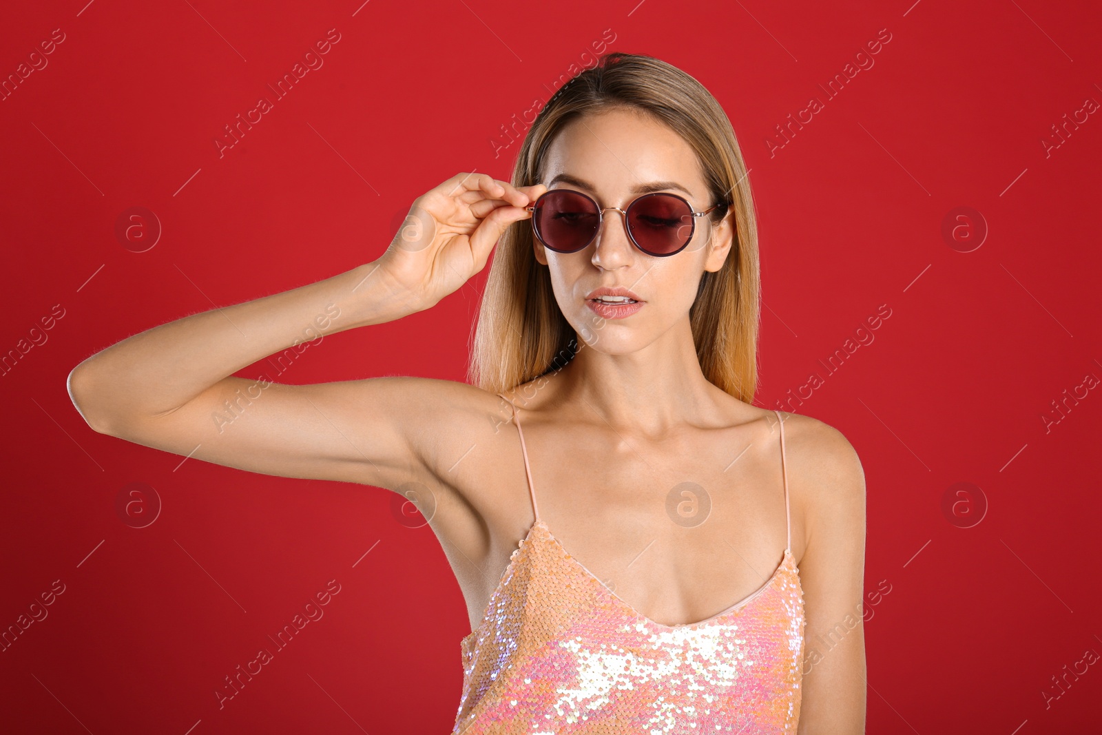 Photo of Beautiful woman in stylish sunglasses on red background