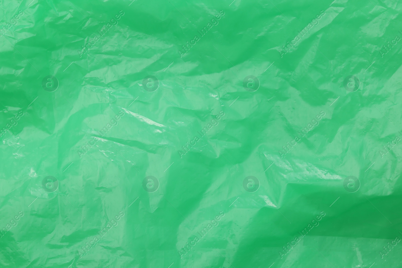 Photo of Crumpled green plastic bag as background, top view