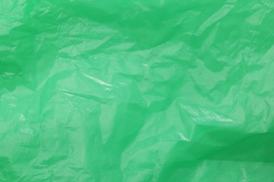 Photo of Crumpled green plastic bag as background, top view