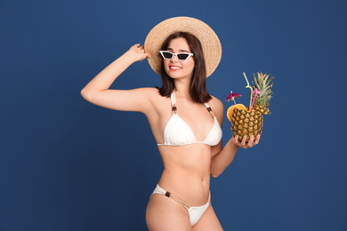 Photo of Beautiful woman in stylish bikini holding tropical cocktail on blue background