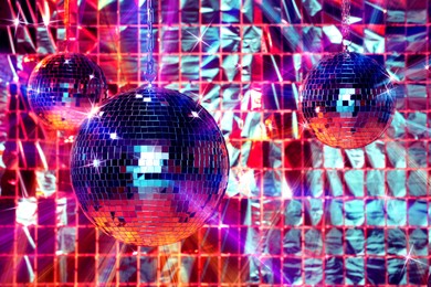 Image of Shiny disco balls against foil party curtain under color lights