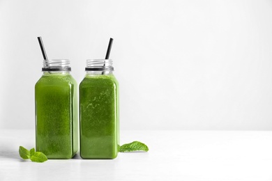 Photo of Bottles with delicious detox juice on light background