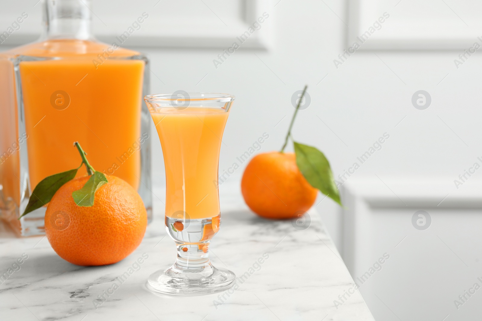 Photo of Delicious tangerine liqueur and fresh fruits on white marble table, space for text