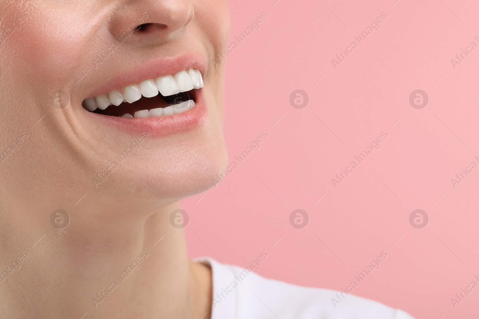 Photo of Woman with clean teeth smiling on pink background, closeup. Space for text