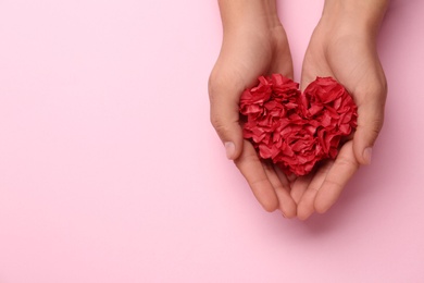 Woman holding red heart on pink background, top view. Space for text