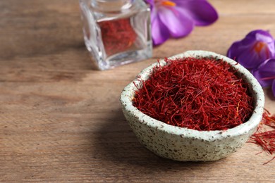 Photo of Dried saffron and crocus flowers on wooden table. Space for text