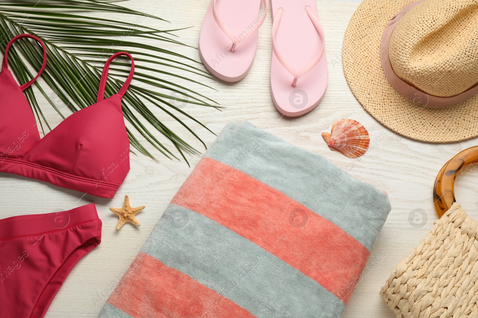 Photo of Towel and different beach accessories on white wooden background, flat lay