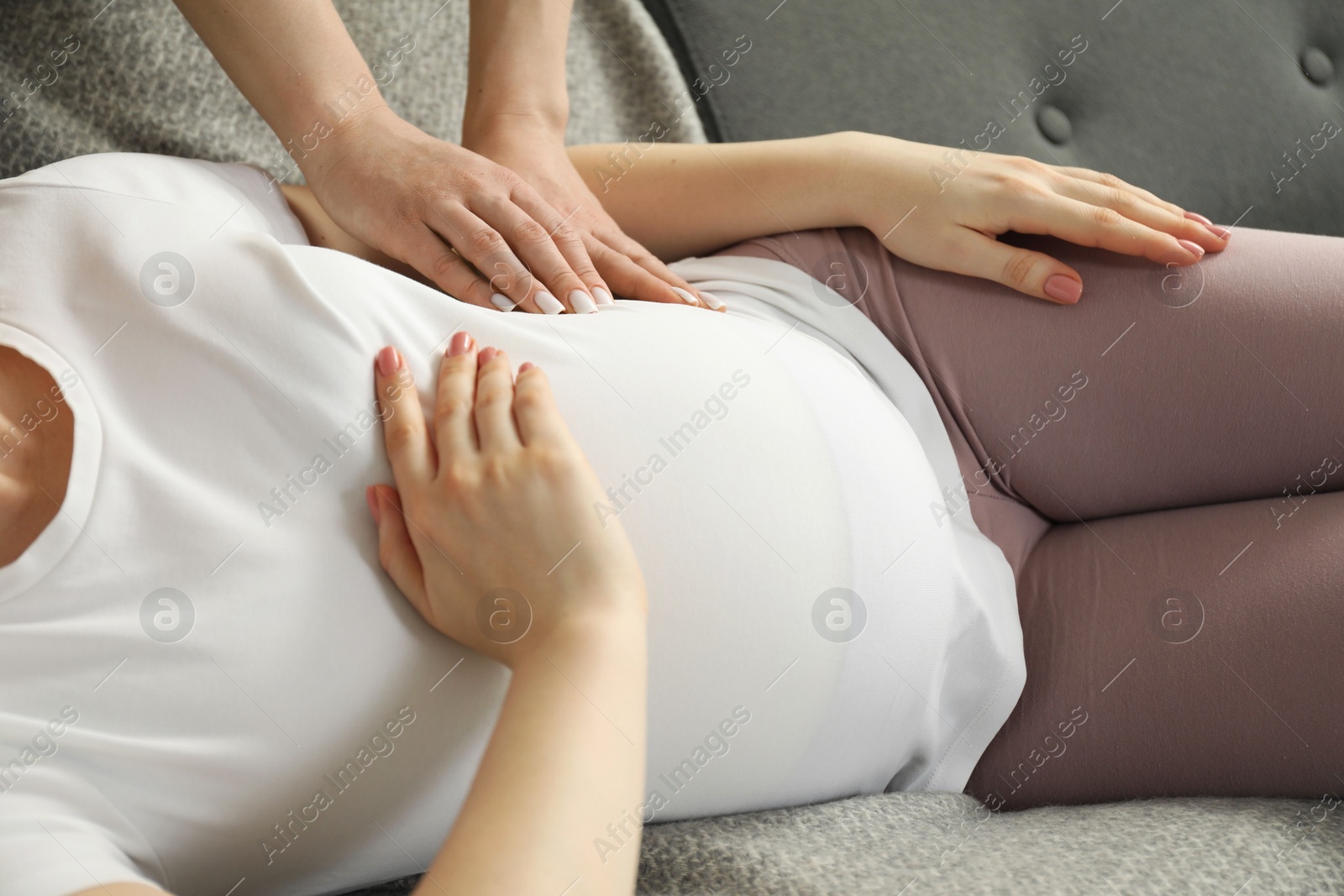 Photo of Doula taking care of pregnant woman at home, closeup. Preparation for child birth