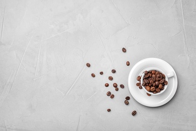 Ceramic cup with coffee beans on light background, top view