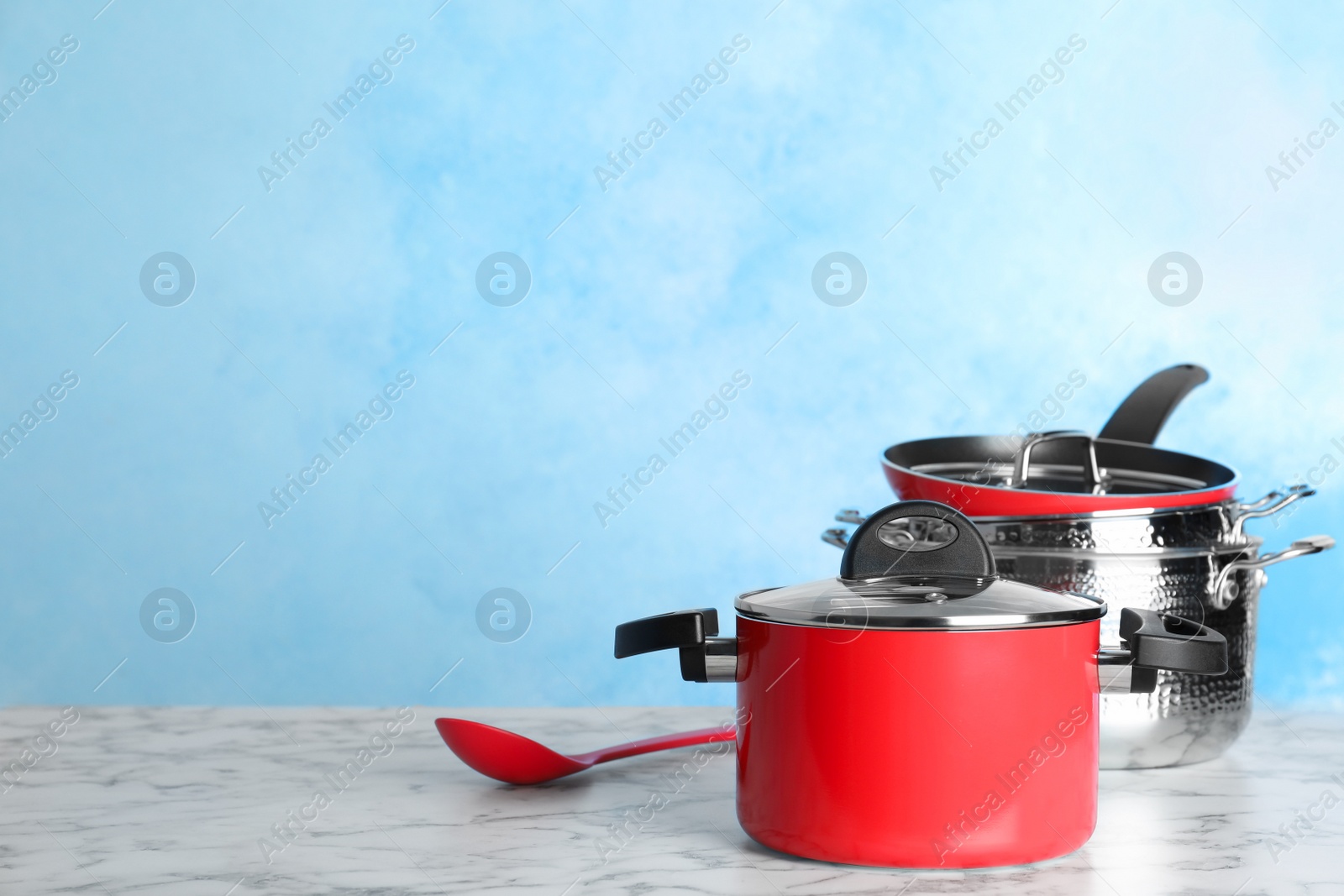 Photo of Set of clean cookware on table against color background. Space for text