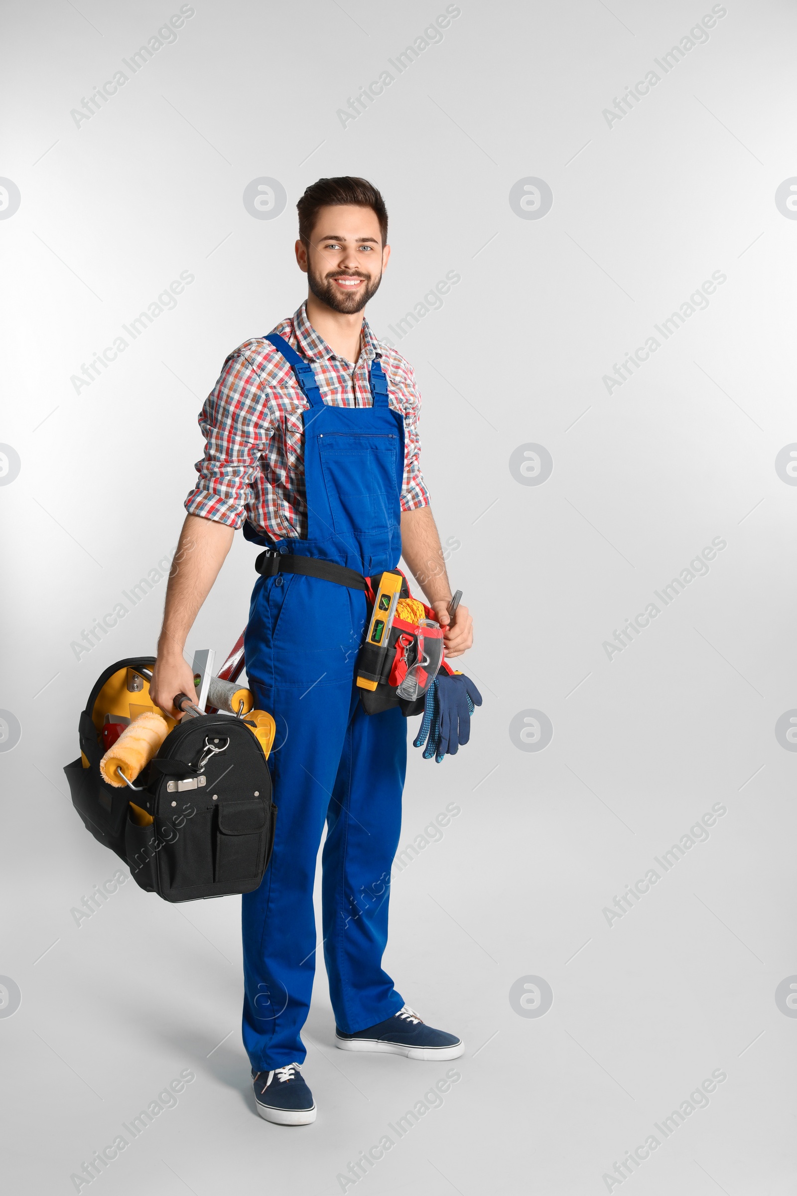 Photo of Full length portrait of construction worker with tools on light background. Space for text