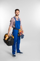 Full length portrait of construction worker with tools on light background. Space for text