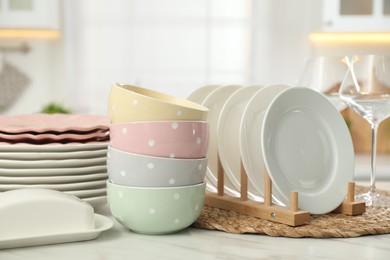 Photo of Clean plates, bowls, butter dish and glasses on white marble table in kitchen