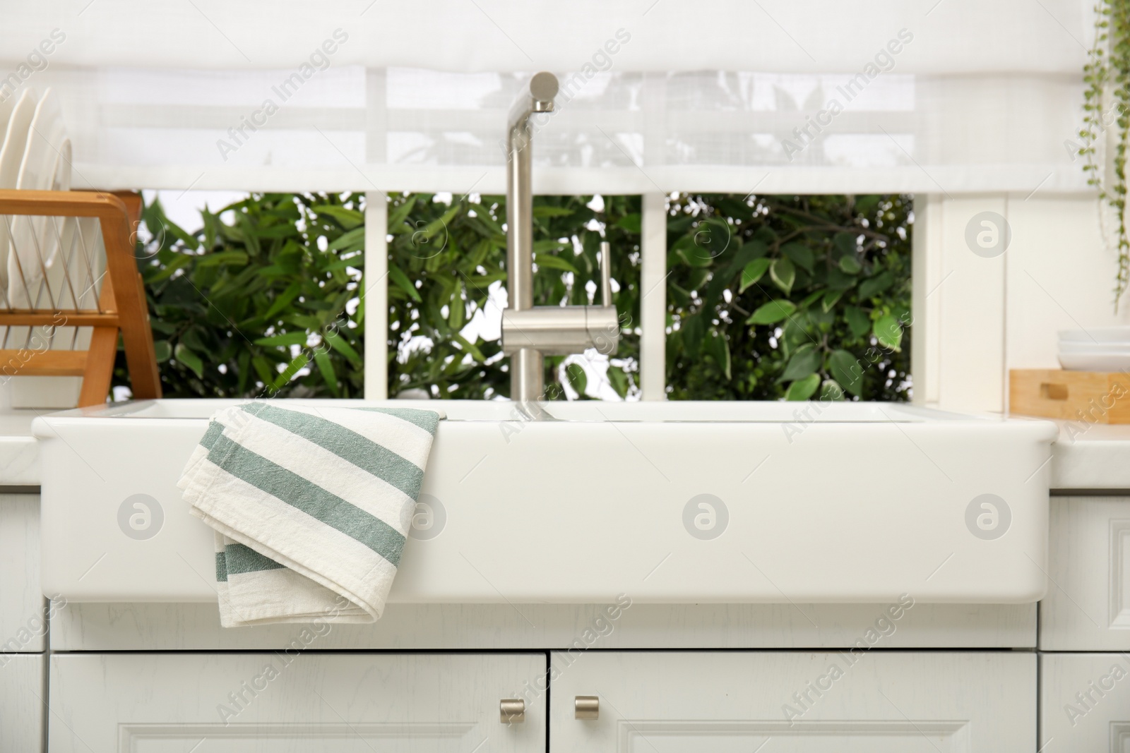 Photo of Clean towel hanging on white sink in kitchen