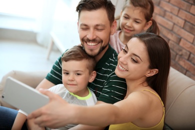 Young woman taking selfie with her family at home