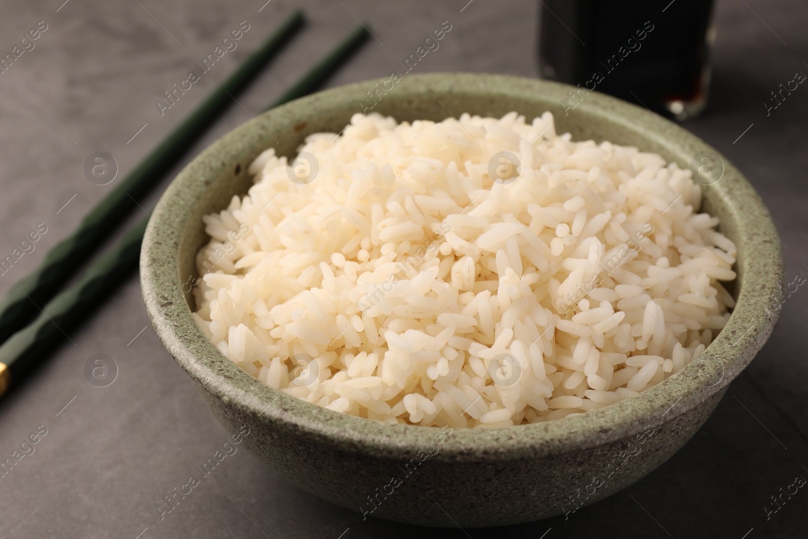 Photo of Delicious rice in bowl on grey table, closeup