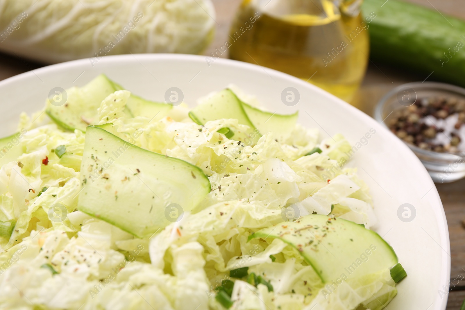 Photo of Tasty salad with Chinese cabbage, cucumber and green onion in bowl on table, closeup