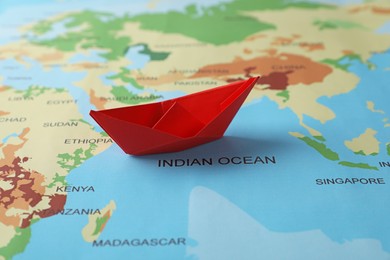 Photo of One red paper boat on world map