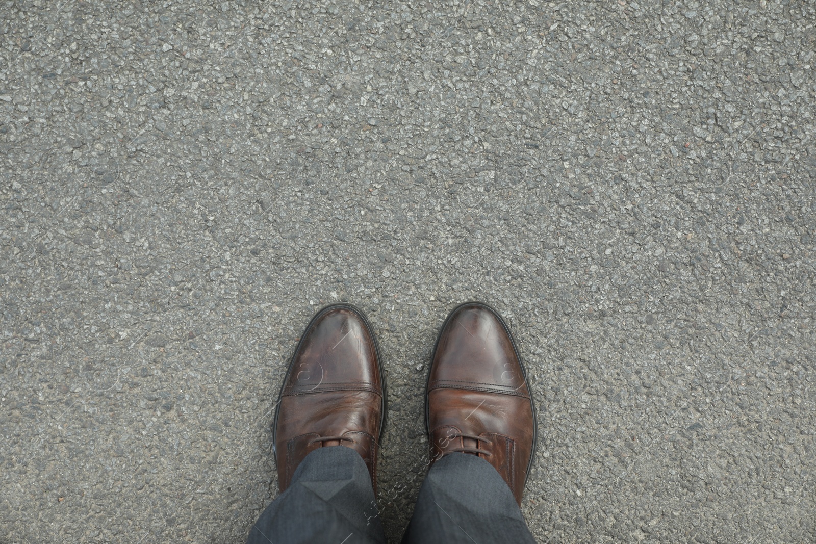 Photo of Man in brown shoes standing on asphalt, top view. Space for text