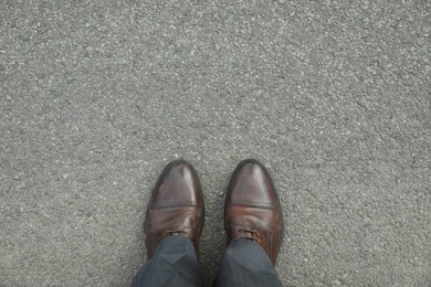 Photo of Man in brown shoes standing on asphalt, top view. Space for text