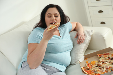 Photo of Lazy overweight woman eating pizza at home