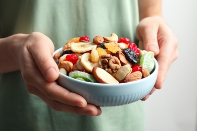 Photo of Young woman holding plate with different dried fruits and nuts, closeup