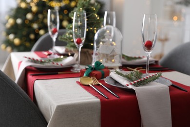 Photo of Christmas table setting with festive decor and dishware indoors