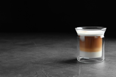 Photo of Glass with delicious coffee drink on grey table against black background. Space for text