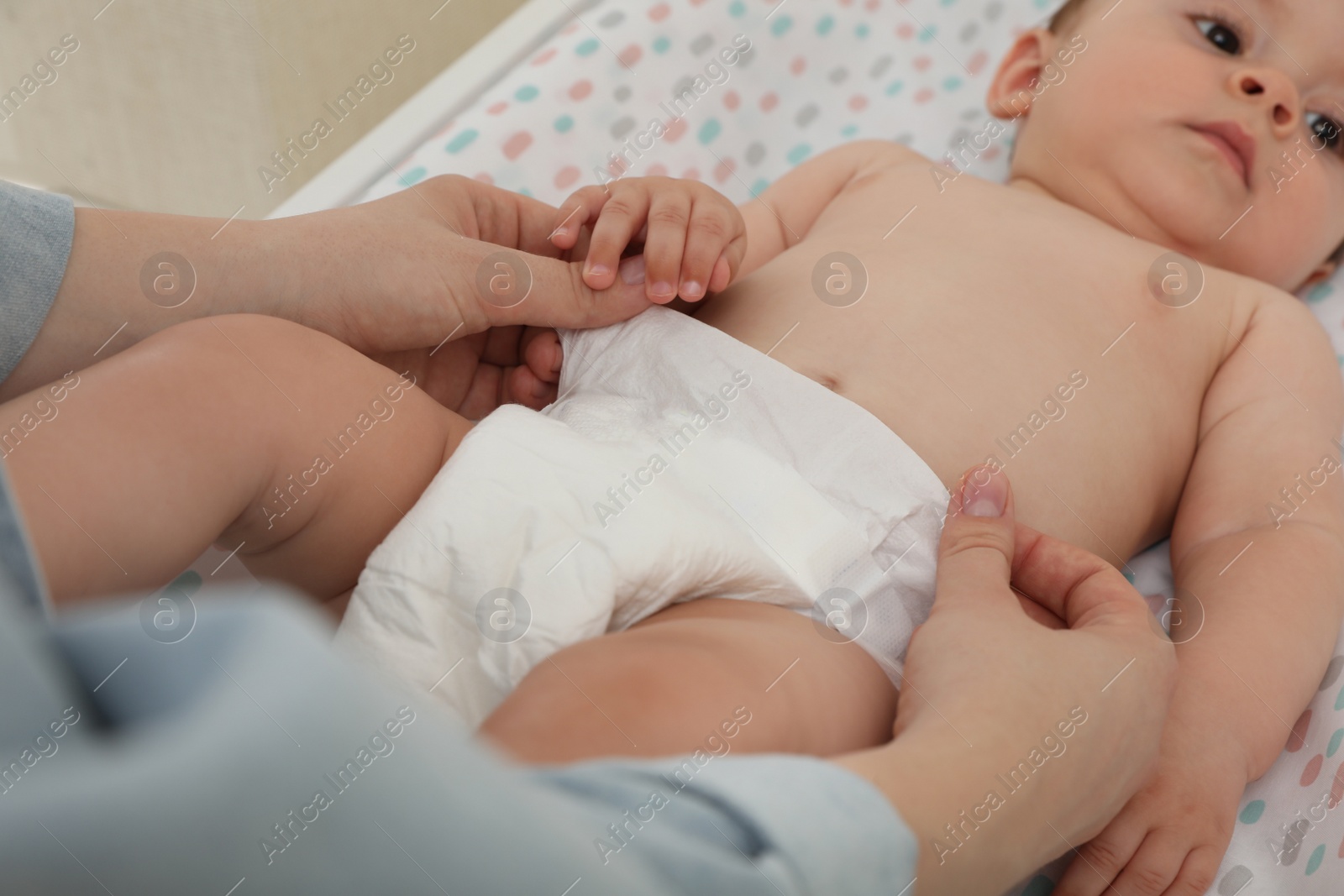 Photo of Mother changing baby's diaper on table, closeup