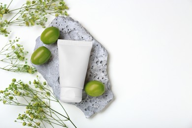 Photo of Tube of cream, olives and flowers on white background, flat lay. Space for text