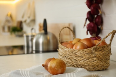 Photo of Fresh onions on countertop in modern kitchen, closeup. Space for text