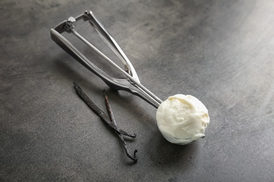 Photo of Scoop with tasty vanilla ice cream on grey background