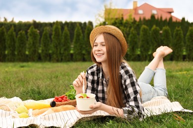 Happy girl having picnic on green grass in park