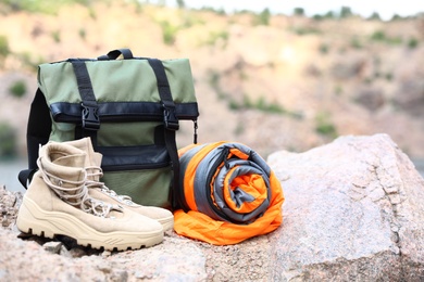 Backpack with sleeping bag and boots outdoors on sunny day. Space for text