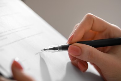Photo of Woman signing documents on light gray background, closeup