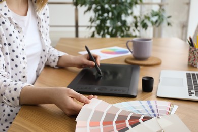 Professional designer with graphic tablet at wooden table, closeup