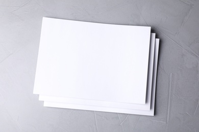 Photo of Blank paper sheets on light grey stone background, top view. Mock up for design