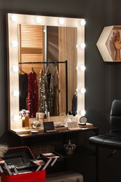 Photo of Makeup room. Stylish mirror with light bulbs and beauty products on dressing table indoors