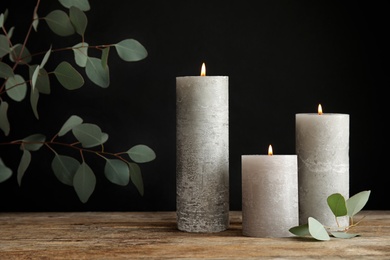 Photo of Composition with burning candles on table against black background. Space for text