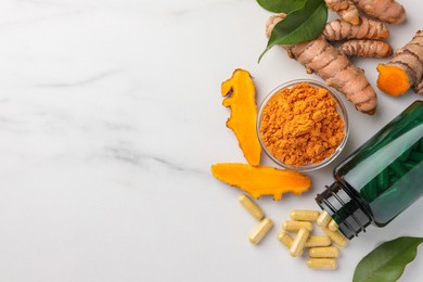 Aromatic turmeric powder, pills and raw roots on white marble table, flat lay. Space for text