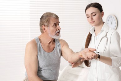 Orthopedist examining patient with injured arm in clinic