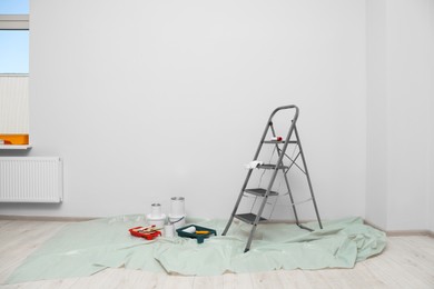 Photo of Metallic folding ladder and painting tools indoors, space for text