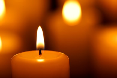 Photo of Burning candle on blurred background, closeup. Space for text