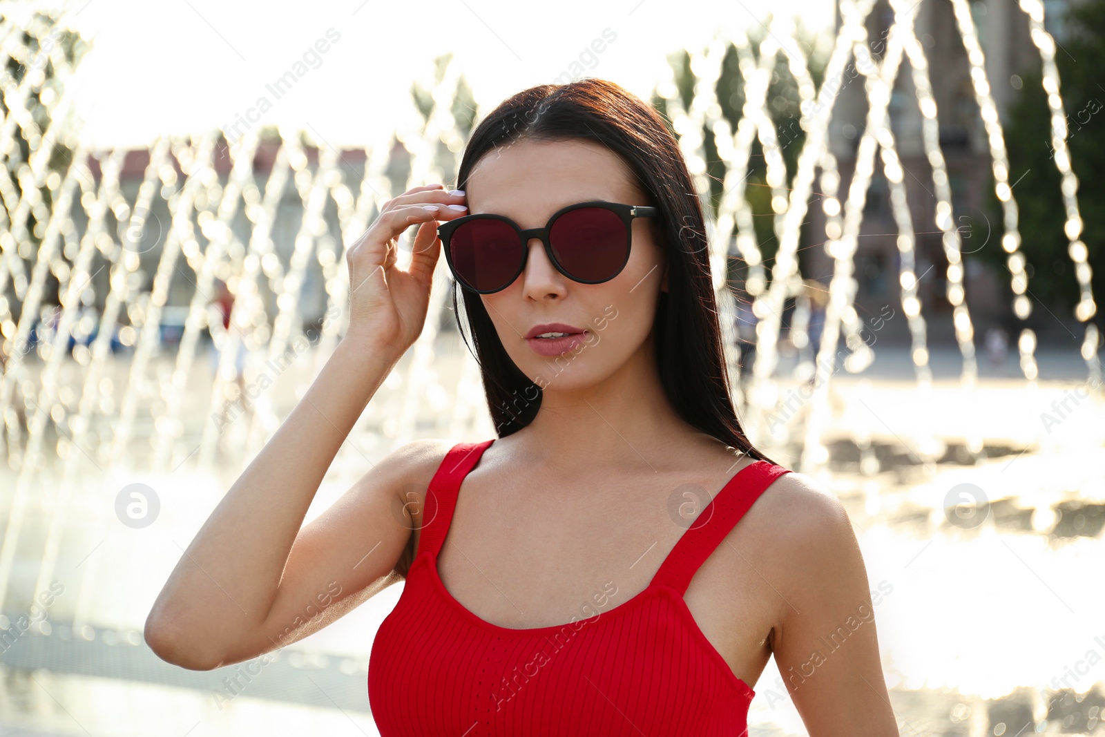 Photo of Beautiful young woman wearing stylish sunglasses outdoors