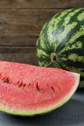 Photo of Tasty whole and cut watermelons on grey wooden table, closeup