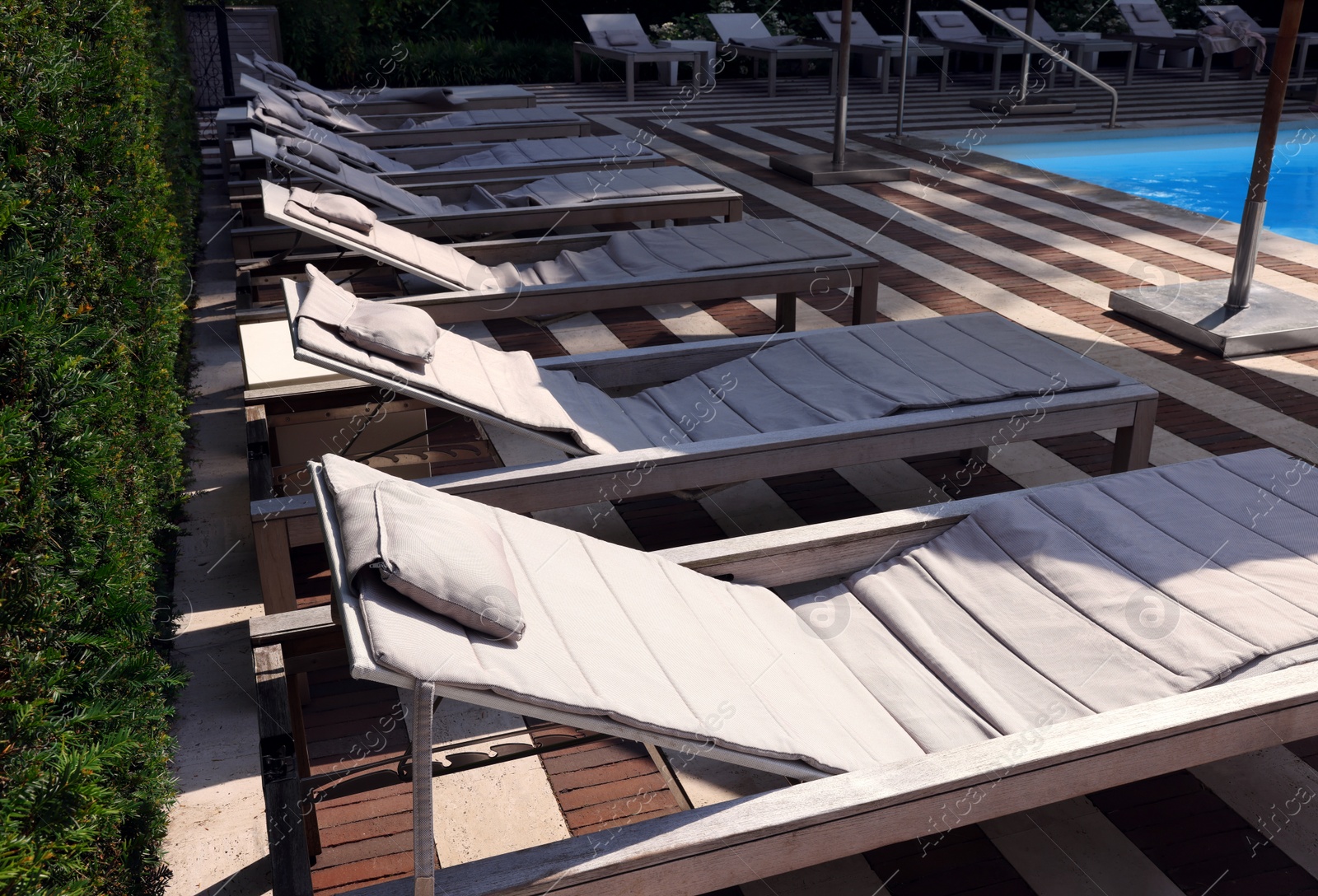 Photo of Many empty sunbeds near outdoor swimming pool at resort