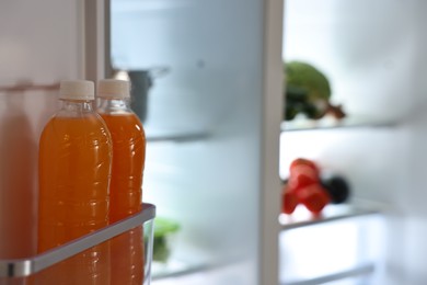 Open refrigerator with bottles of drink indoors, space for text