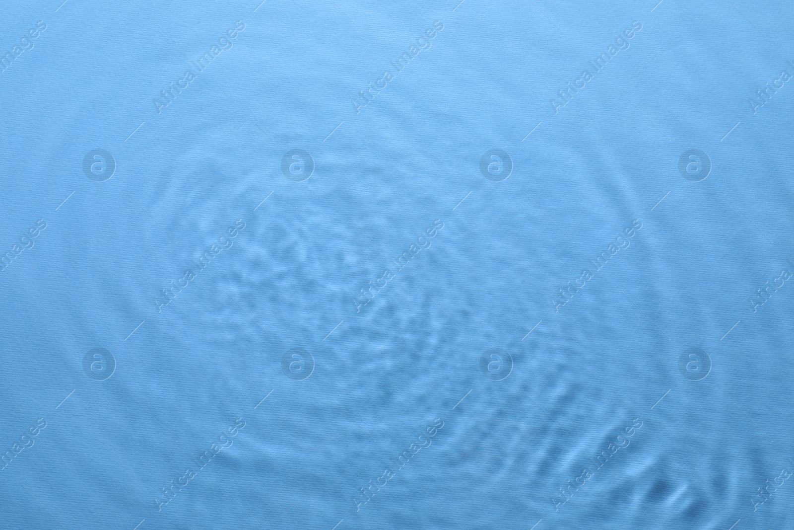 Image of Rippled surface of clear water on light blue background, top view